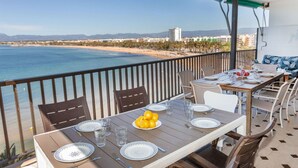Ein Balkon mit Esstisch, der Blick auf Strand und Stadt bietet.