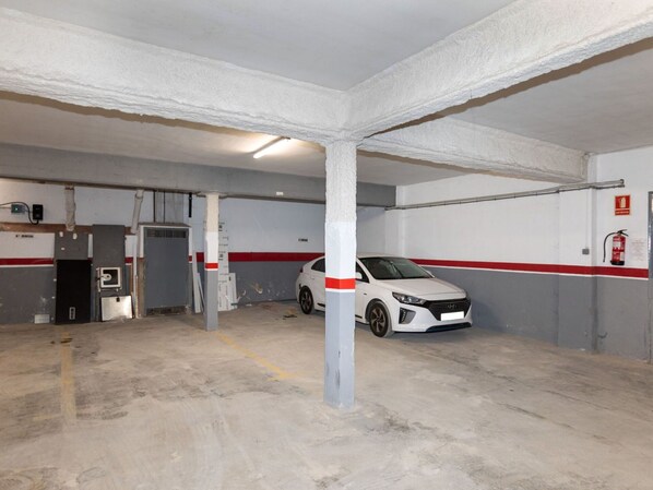A parking garage with concrete floors, white walls, and red stripes.