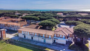 An aerial view of a residential area with terracotta-roofed buildings, surrounded by green trees and a clear blue sky. - Beautiful apartment for 5 guests with WIFI, TV and balcony (Cecina)