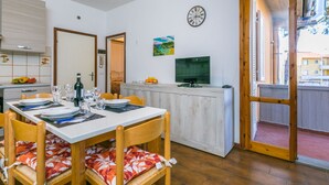 A dining area with a table set for four, a television, and a clock on the wall. - Beautiful apartment for 5 guests with WIFI, TV and balcony (Cecina)