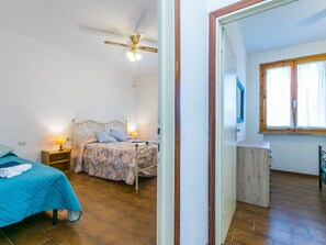 A bedroom with a bed, bedside tables, a ceiling fan, and a window. - Beautiful apartment for 5 people with WIFI, TV and balcony (Cecina)