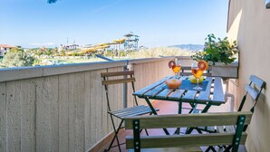 An outdoor patio with a table and chairs, overlooking a water park and distant hills. - Beautiful apartment for 5 guests with WIFI, TV and balcony (Cecina)