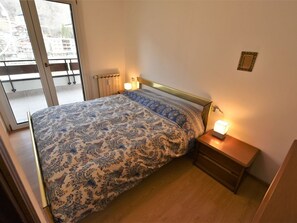 A bedroom with a bed, two bedside tables, a window, and a view of buildings outside. - Nice apartment for 5 people with WIFI, TV and terrace (Aprica)