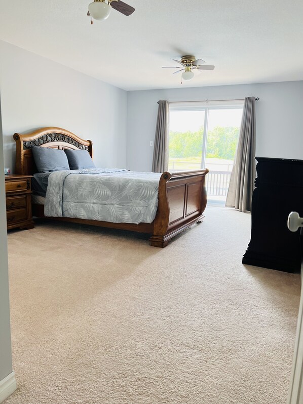 A bedroom with a bed, nightstand, dresser, and a ceiling fan.