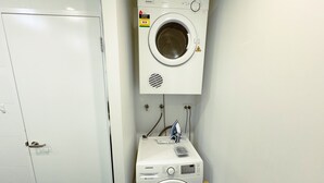 A compact laundry area with a Samsung washing machine and a dryer, both white, in a small room with a white door.