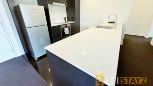 A modern kitchen with a large island, built-in oven, and stainless steel appliances.