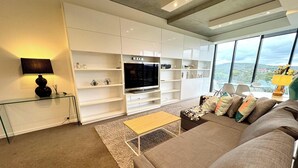 Un salon moderne comprenant un canapé, une table basse, un téléviseur et des étagères intégrées.