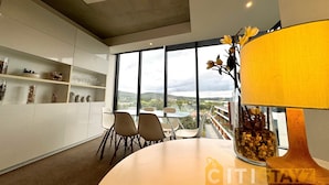 Un salon moderne doté d’une grande fenêtre, d’un coin repas avec des chaises et une table.