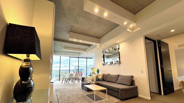Un salon moderne avec un canapé, une table basse et une grande fenêtre donnant sur la ville.