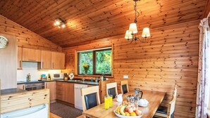 A wooden cabin interior with a kitchen, dining area, and a large window. - Nice apartment in villa for 6 guests with WIFI, TV, patio and panoramic view (Inverness)