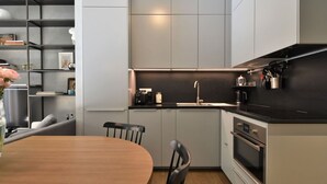 Une cuisine moderne avec des meubles gris, un plan de travail noir et des appareils électroménagers en acier inoxydable.