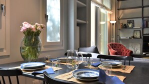 Un coin repas avec une table dressée pour quatre personnes, un vase de fleurs et une bibliothèque en arrière-plan.