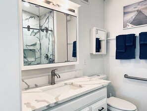 Une salle de bain avec un lavabo en marbre, un grand miroir, un porte-serviettes avec des serviettes et des toilettes.
