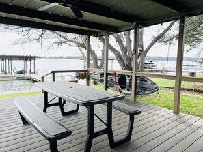 A covered picnic area with a table and benches overlooking a lake.