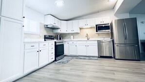 Una cocina moderna con armarios blancos, electrodomésticos de acero inoxidable y suelo de madera.