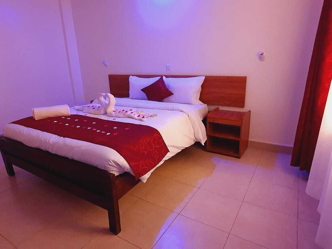 A neatly made bed with a red blanket and a swan-shaped pillow.