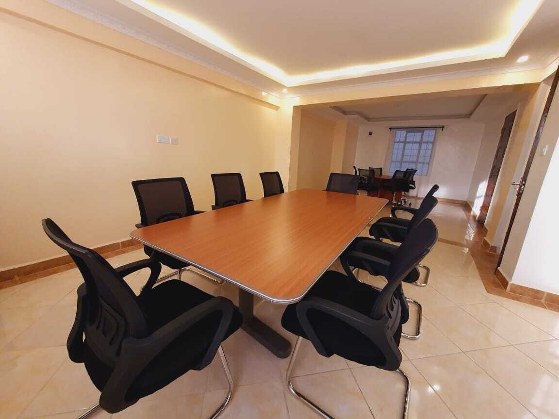 Un salón de conferencias con una gran mesa de madera y sillas negras.