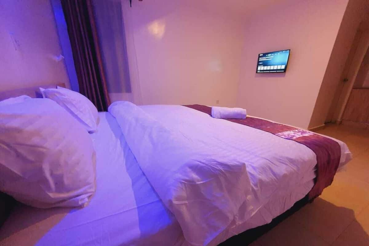 Quarto de hotel com cama, televisão na parede e cortina.