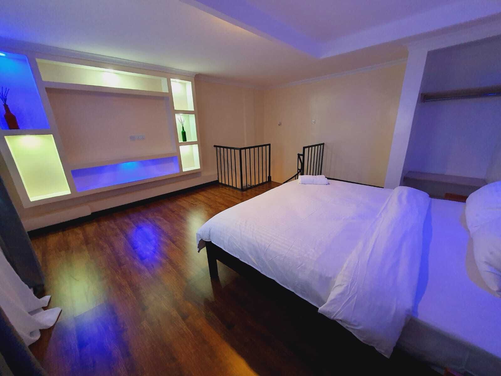 A modern bedroom with a large bed, built-in shelving, and a small balcony.