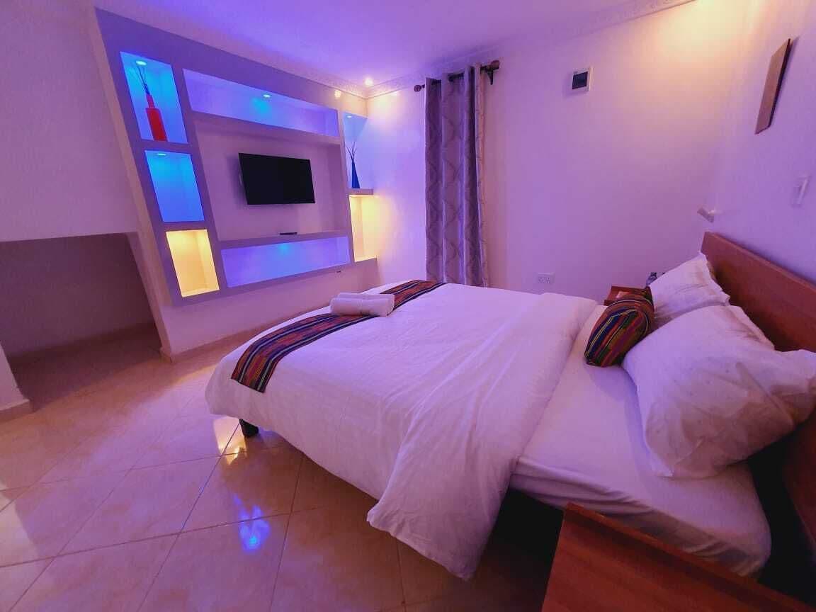 Une chambre à coucher avec un lit, un téléviseur fixé au mur et un luminaire fixé au mur.