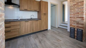 A modern kitchen with wooden cabinets, a stainless steel sink, and a brick wall.