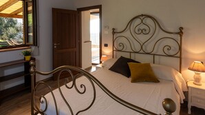 A bedroom with a metal bed frame, a bedside table with a lamp, and a window with a view of the outdoors.