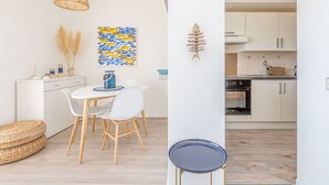 A modern kitchen with white cabinets, a built-in oven, and a dining area with a white table and chairs.