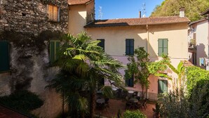 A courtyard with stone buildings, a palm tree, and outdoor seating.