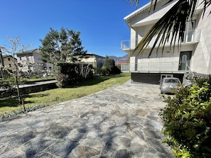 A courtyard with a stone pathway leading to a building with a balcony. - Lovely apartment in villa for 6 people with A/C, WIFI, TV and patio (Dervio)