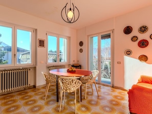A dining area with a round table and chairs, large windows, and a radiator. - Lovely apartment in villa for 6 people with A/C, WIFI, TV and patio (Dervio)