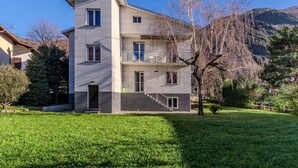 A modern two-story building with a flat roof, multiple windows, and a staircase leading to the upper floor. - Cosy apartment in villa for 6 guests with WIFI, TV, patio and pets allowed (Dervio)
