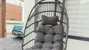 A hanging chair with a cushioned seat and backrest, mounted on a metal stand with wheels, positioned outdoors against a building facade. - Your cool oasis home away from home. Breath taking views for relaxation  (Ocho Rios)