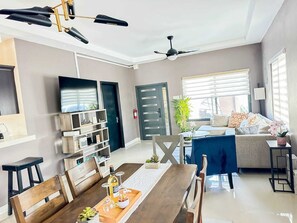 A modern living room with a dining area, a TV, and a ceiling fan. - Your cool oasis home away from home. Breath taking views for relaxation  (Ocho Rios)