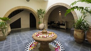 A courtyard with a central fountain surrounded by potted plants and a checkered floor pattern. - Dar Nor Riad  (Essaouira)