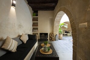 A cozy living room with a black sofa, a fireplace, and a coffee table with decorative items. - Dar Nor Riad (Essaouira)