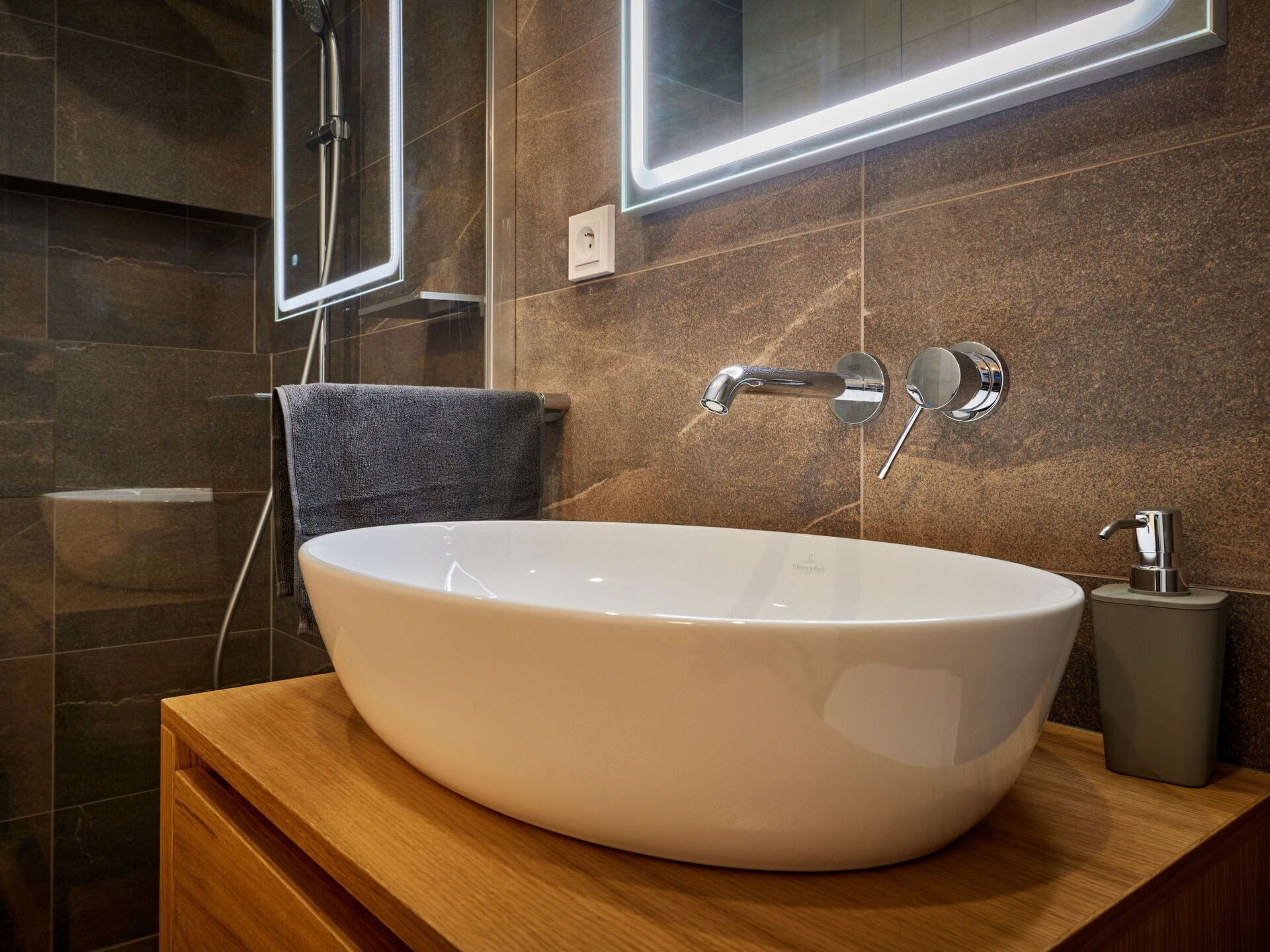 A modern bathroom with a large oval sink, a mirror, and a towel rack.