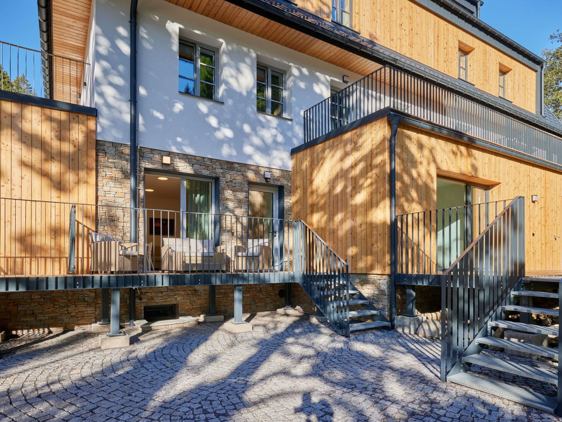 A modern building with a stone facade, wooden balconies, and a cobblestone courtyard.