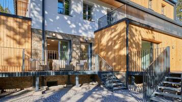 A modern building with a stone facade, wooden balconies, and a cobblestone courtyard.