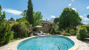 A swimming pool with a stone border, surrounded by lush greenery and a stone building in the background. - Wonderful private villa for 10 guests with WIFI, private pool, TV, pets allowed and panoramic view (Civitella In Val Di Chiana)