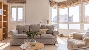A living room with a sofa, a coffee table with glasses, and a vase with flowers.