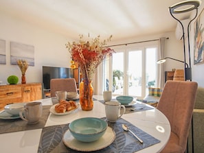Enjoy a romantic dinner for two in this inviting dining area with a round table, vase of flowers, and a view of the outdoors.