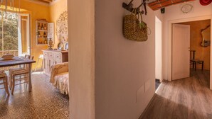 Une pièce chaleureuse avec un plafond en bois, un coin repas avec une table et des chaises, et un mur orné d’un panier décoratif et d’une horloge.