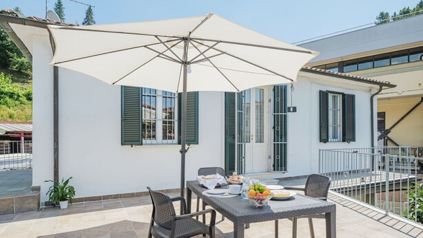 A patio with a table set for two, a large umbrella, and a view of a white building with green shutters. - Stunning  villa for 2 people with WIFI, TV and terrace (Massa)