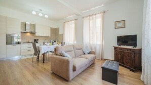 A modern living room with a sofa, a dining table, and a kitchen in the background. - Stunning  villa for 2 people with WIFI, TV and terrace (Massa)