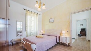 A bedroom with a bed, bedside lamps, a mirror, a window with curtains, and a door leading to another room. - Stunning  villa for 2 people with WIFI, TV and terrace (Massa)