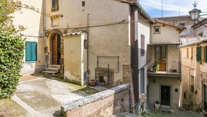 Une rue étroite bordée de bâtiments traditionnels, un mur de briques et une petite cour.