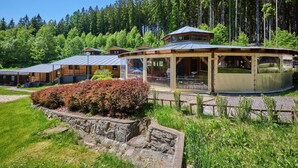 Eine Lodge mit einem gläsernen Essbereich, Holzhütten und einer Steinmauer zur Geländeerhaltung.