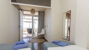A hotel room with two beds, a round table, a chair, and a large window. - Cosy apartment for 4 guests with WIFI, TV and terrace (Torroella De Montgrí)