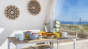 A breakfast setup with a table, breakfast items, and a view of the sea. - Cosy apartment for 4 guests with WIFI, TV and terrace (Torroella De Montgrí)