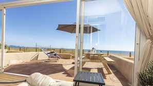 A sunlit patio with a view of the beach, a table with a tablecloth, and a lounge chair. - Cosy apartment for 4 guests with WIFI, TV and terrace (Torroella De Montgrí)